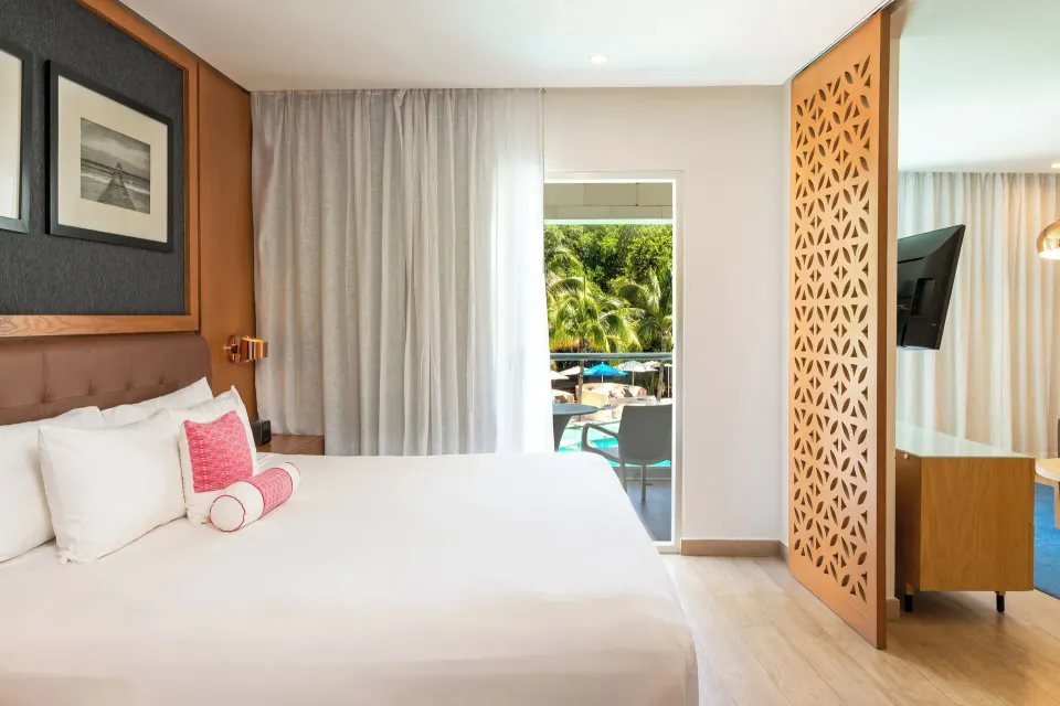 One Bedroom Suite king bed beside balcony and sitting area at The Fives Beach Hotel.