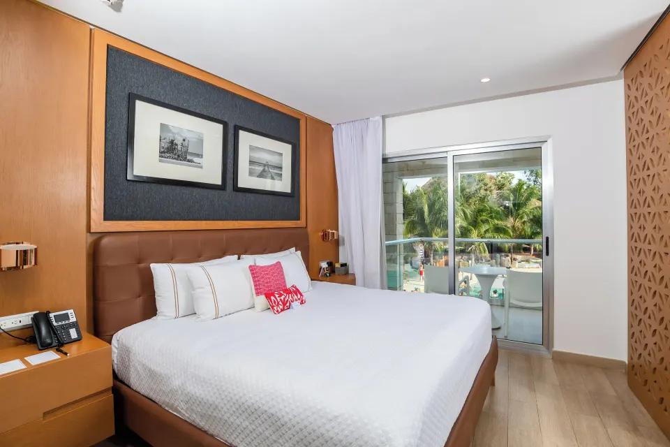 One Bedroom Suite king bed with balcony doors at The Fives Beach Hotel.
