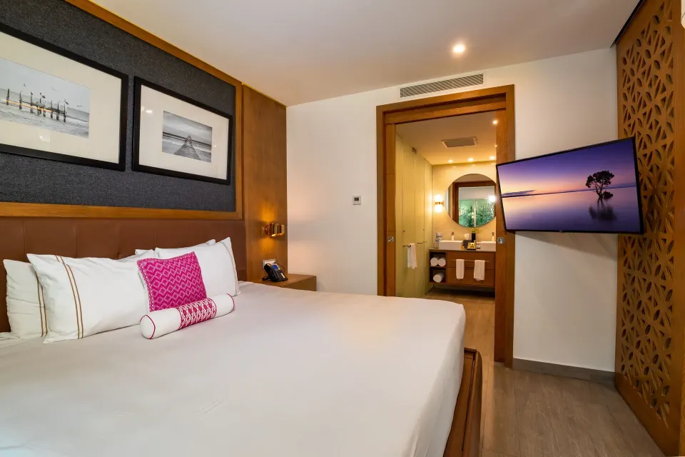 One Bedroom Suite king bed and bathroom doorway at The Fives Beach Hotel.