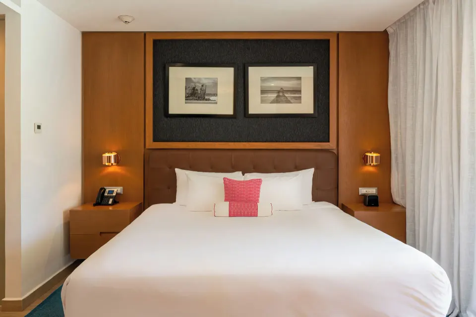 One Bedroom Suite king bed with nightstands and framed art at The Fives Beach Hotel.