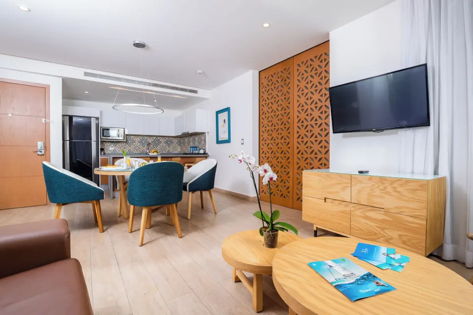 One Bedroom Suite living room with dining table and TV at The Fives Beach Hotel.