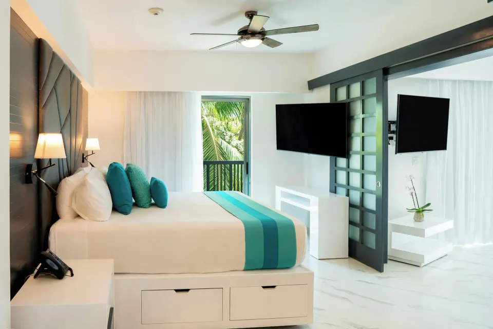 Three Bedroom Suite king bedroom with balcony and TVs at The Fives Beach Hotel.