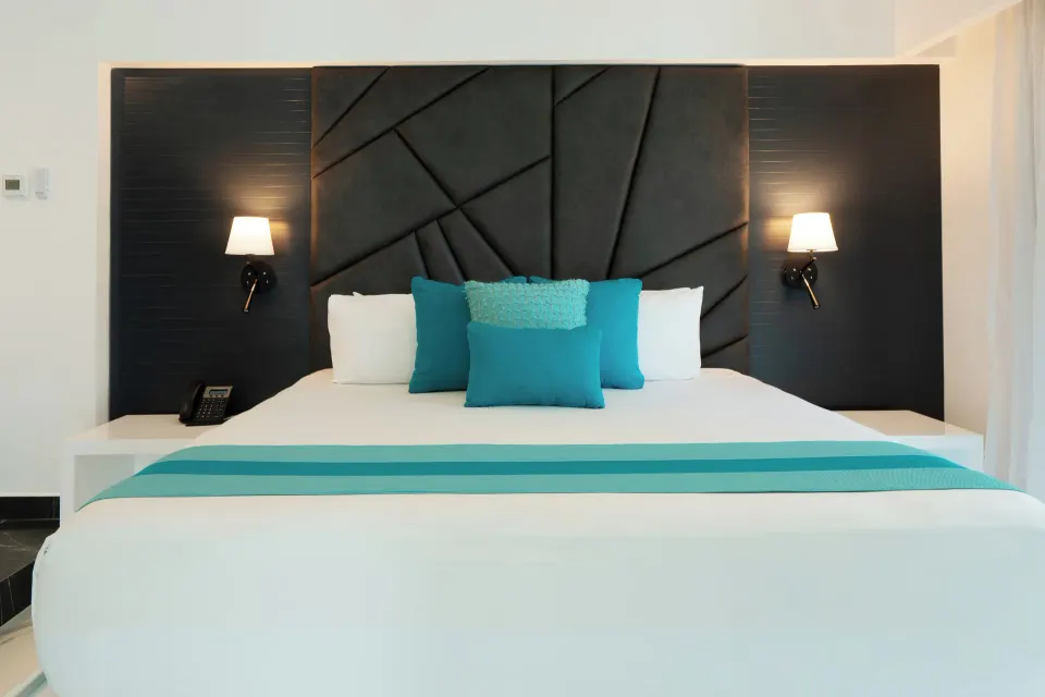 Three Bedroom Suite king bed with dark headboard and turquoise pillows at The Fives Beach Hotel.