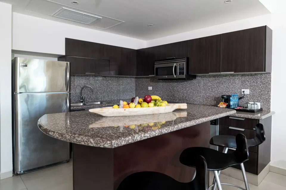 Three Bedroom Suite kitchen with granite counter and bar stools at The Fives Beach Hotel.