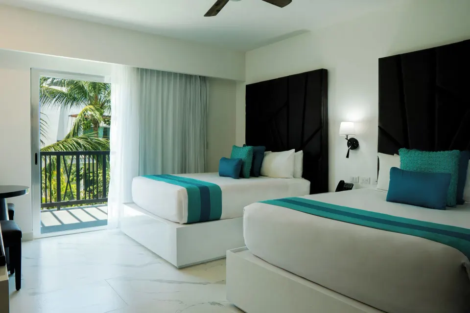 Three Bedroom Suite bedroom with two beds and balcony greenery at The Fives Beach Hotel.