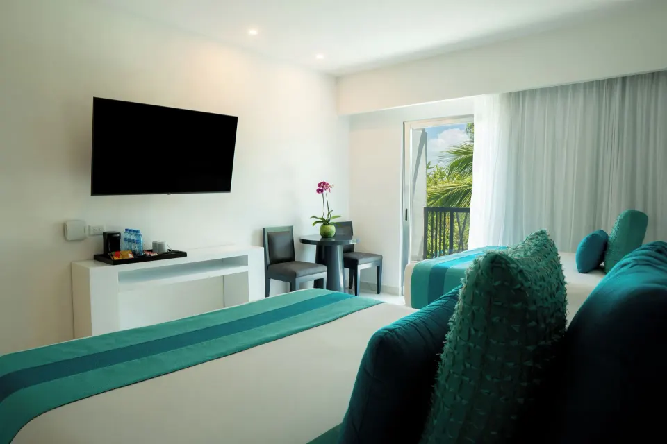 Three Bedroom Suite bedroom with two beds, TV and balcony at The Fives Beach Hotel.