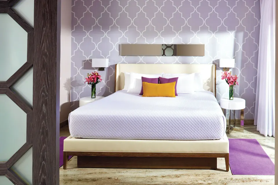 Two Bedroom Suite king bed framed by patterned wall panels at The Fives Beach Hotel.