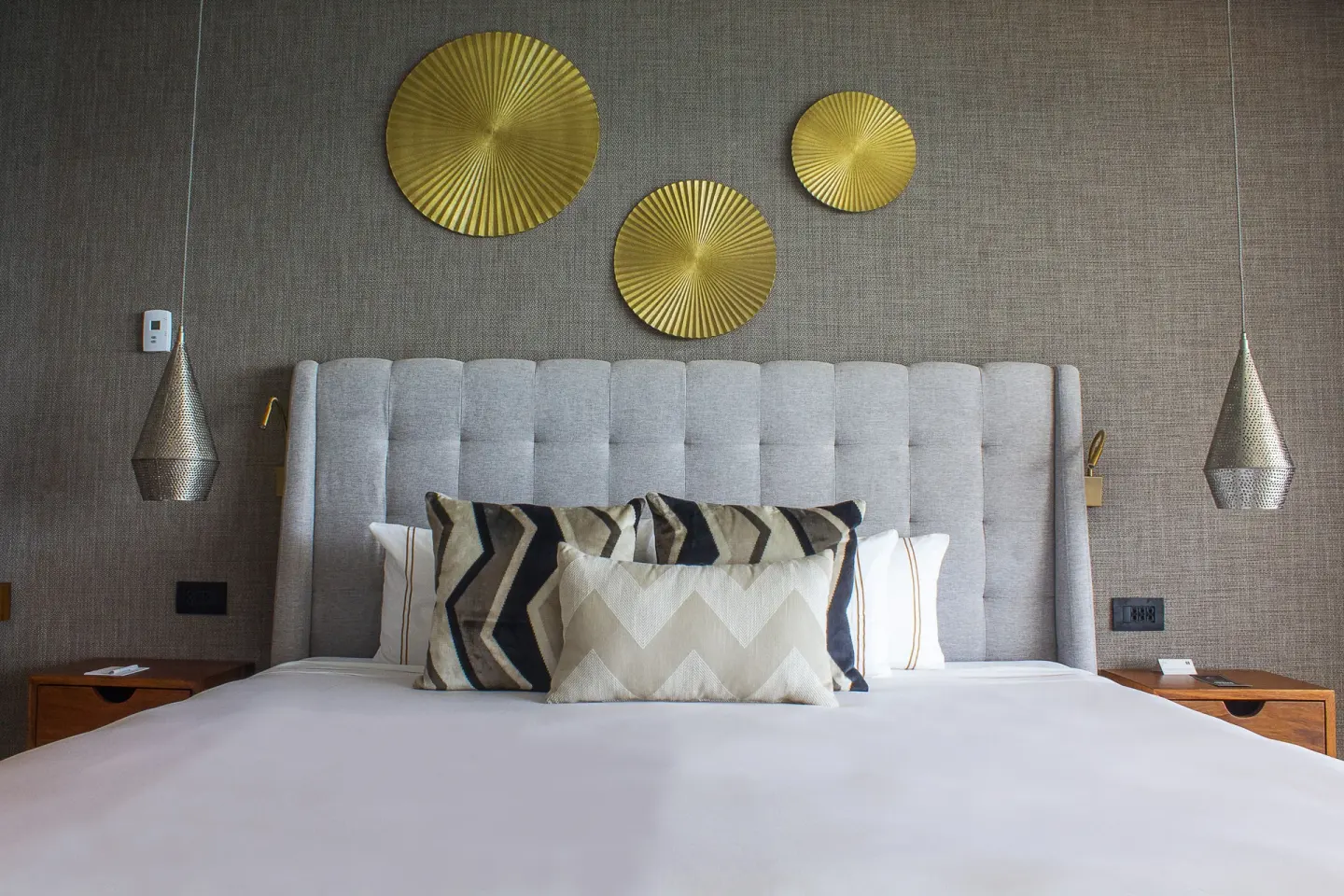 King bed with tufted headboard and gold wall art at The Fives Oceanfront Riviera Maya.