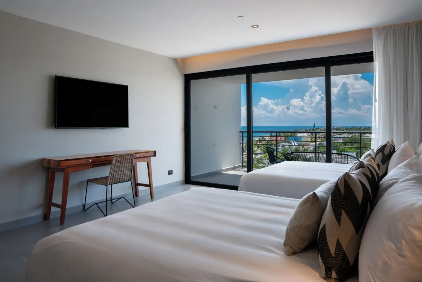 Two-bed guest room with desk and balcony view at The Fives Oceanfront Riviera Maya.