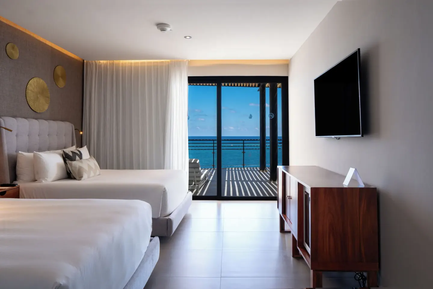 Two-bed ocean view guest room with TV console at The Fives Oceanfront Riviera Maya.