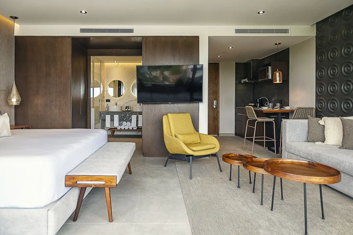 Open suite with king bed, sofa, kitchenette, and bath at The Fives Oceanfront Riviera Maya.