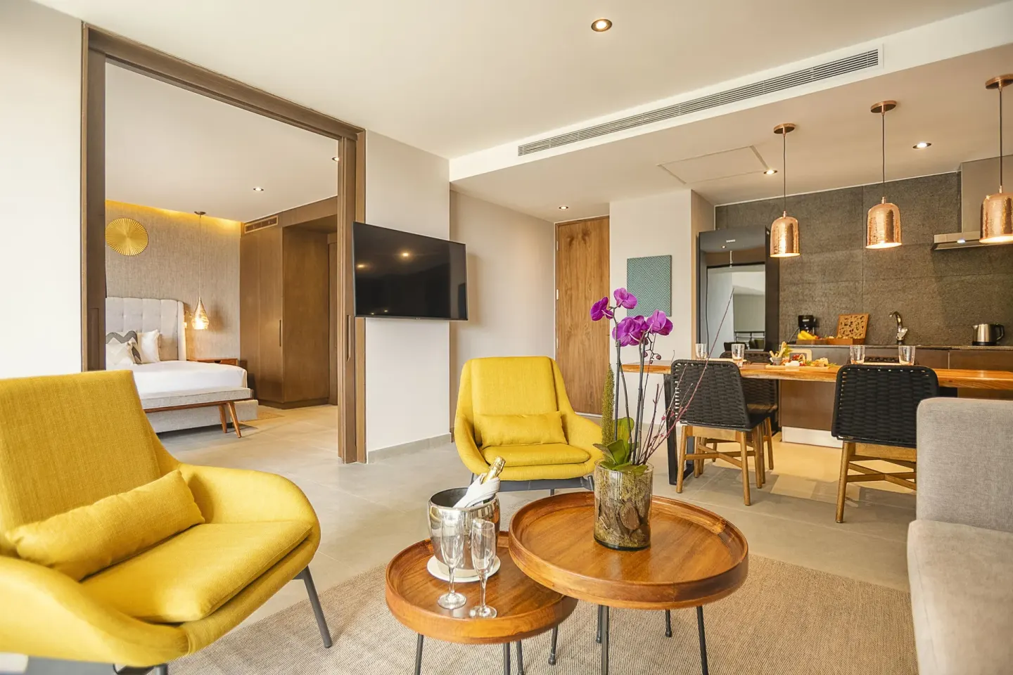 Suite living room with yellow chairs and kitchenette at The Fives Oceanfront Riviera Maya.