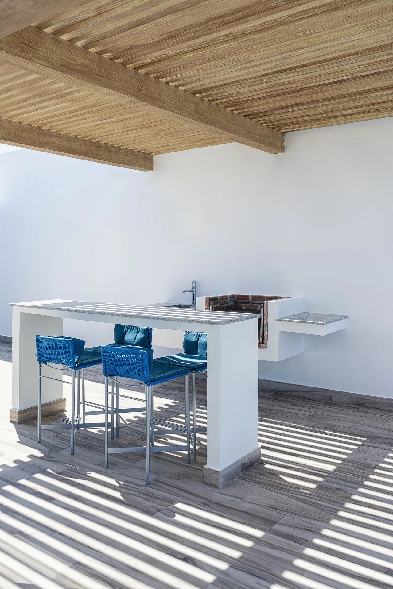 Covered outdoor bar counter with blue stools at The Fives Oceanfront Riviera Maya.