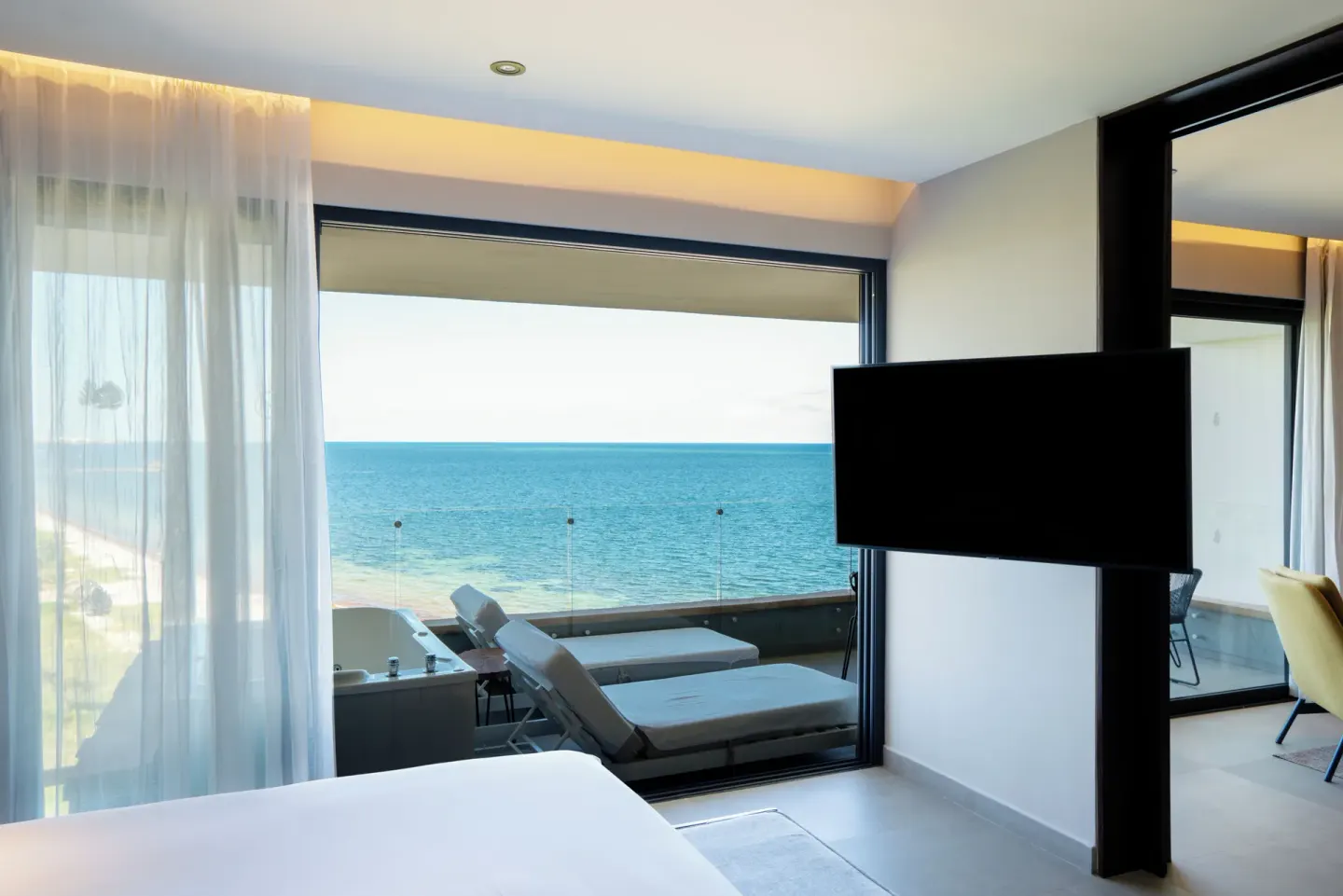 Bedroom TV and balcony ocean view at The Fives Oceanfront Riviera Maya.