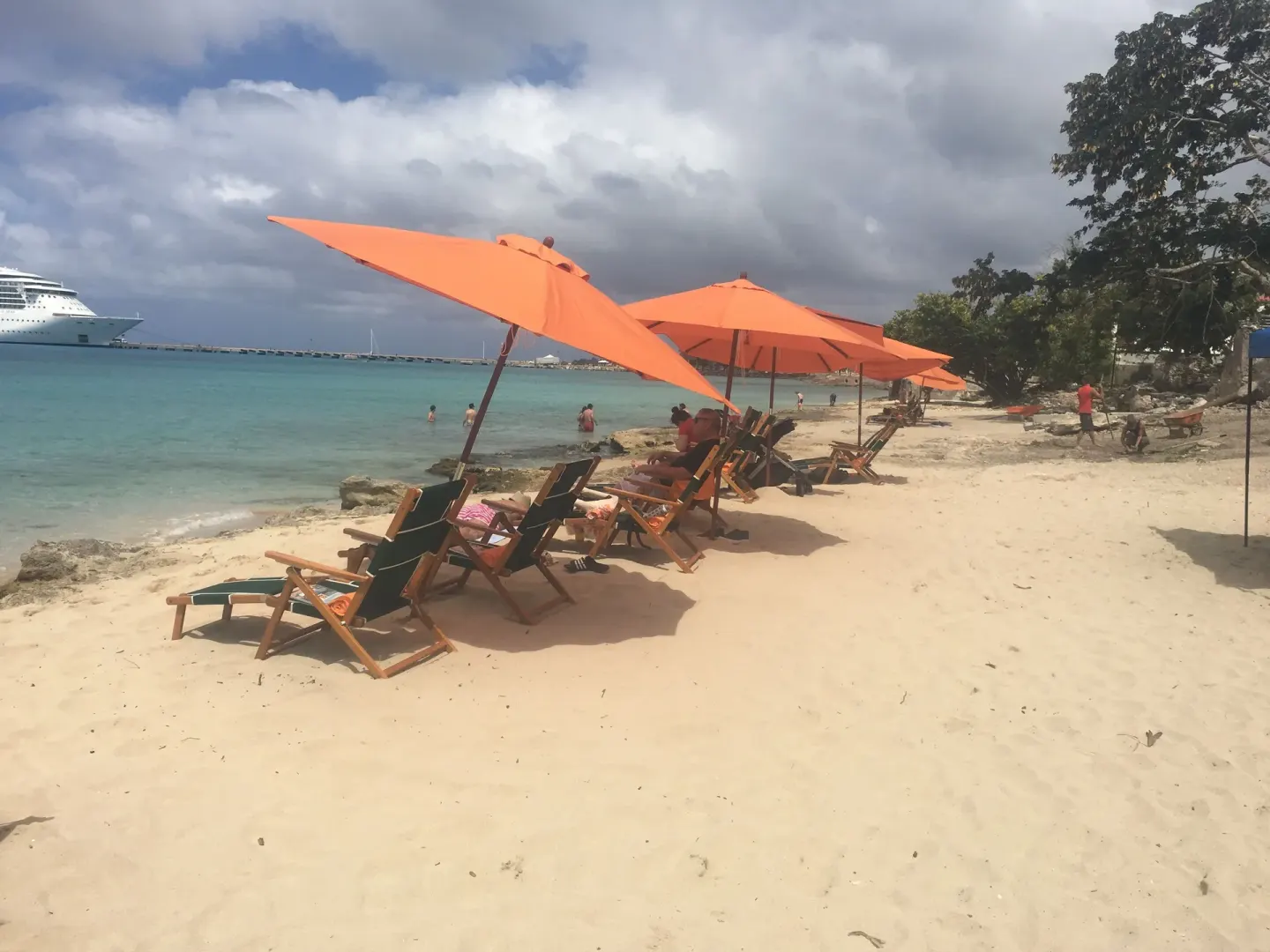 Orange umbrellas and lounge chairs line the beach at The Fred beside turquoise water.