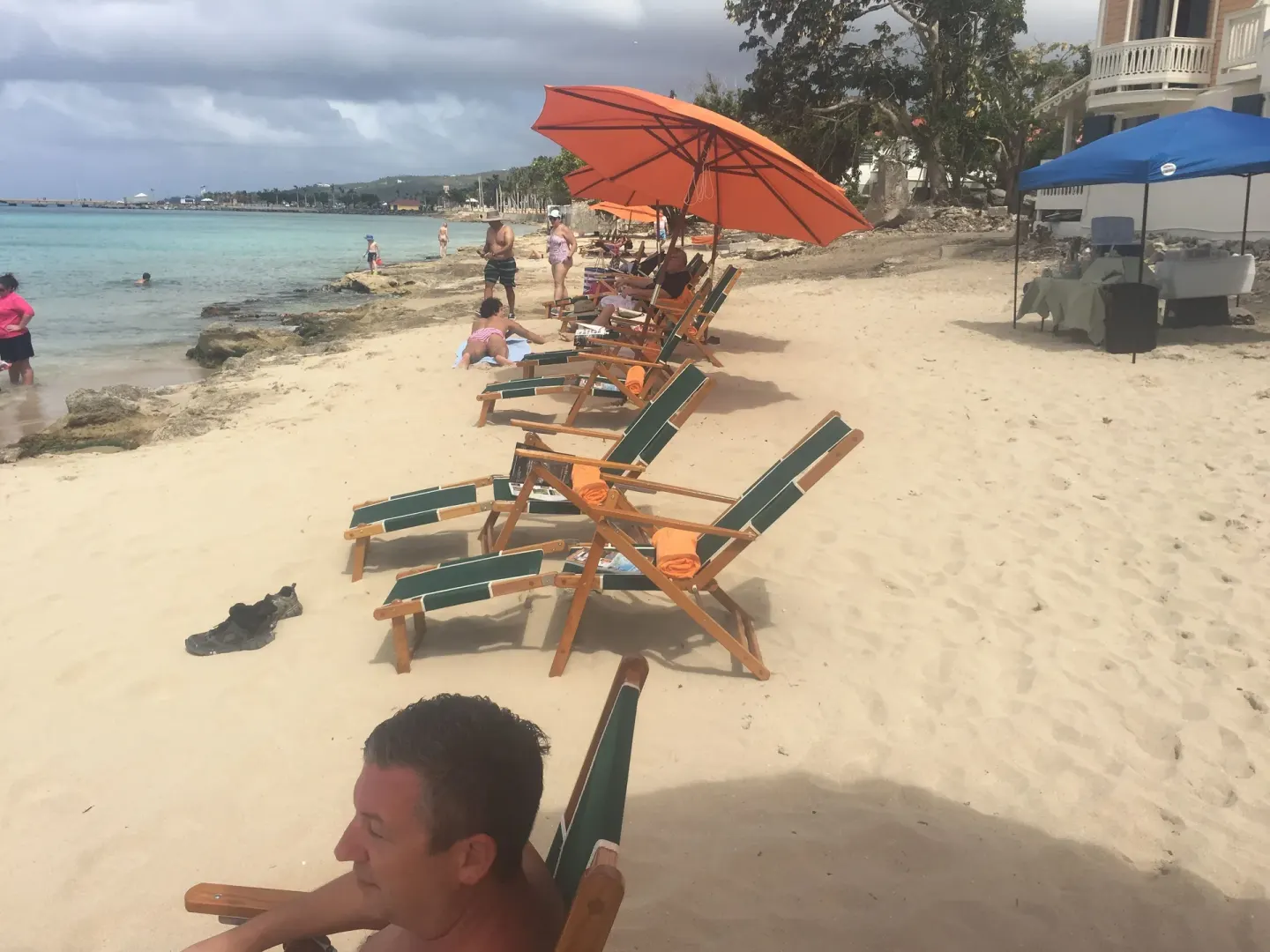 Beach lounge chairs at The Fred lined along the sand beneath orange umbrellas.