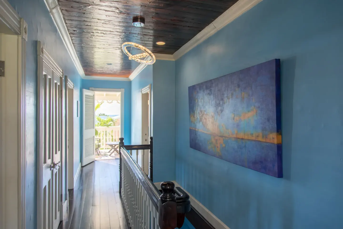 A blue hallway with artwork and an open balcony door is shown at The Fred.