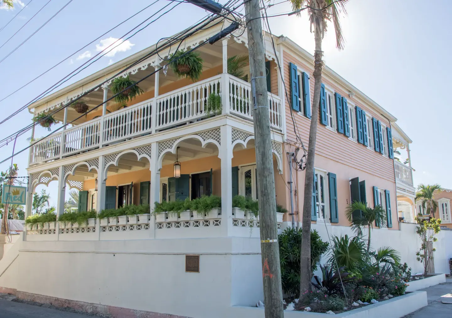 Closer corner view of The Fred exterior with white railings, teal shutters, and garden plants.