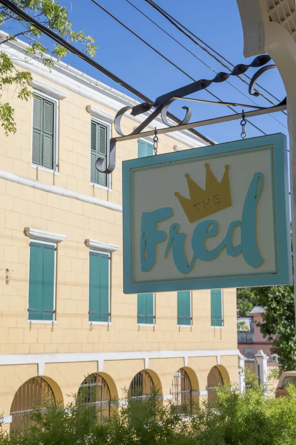 The Fred hanging sign appears outside a yellow building with teal shutters.
