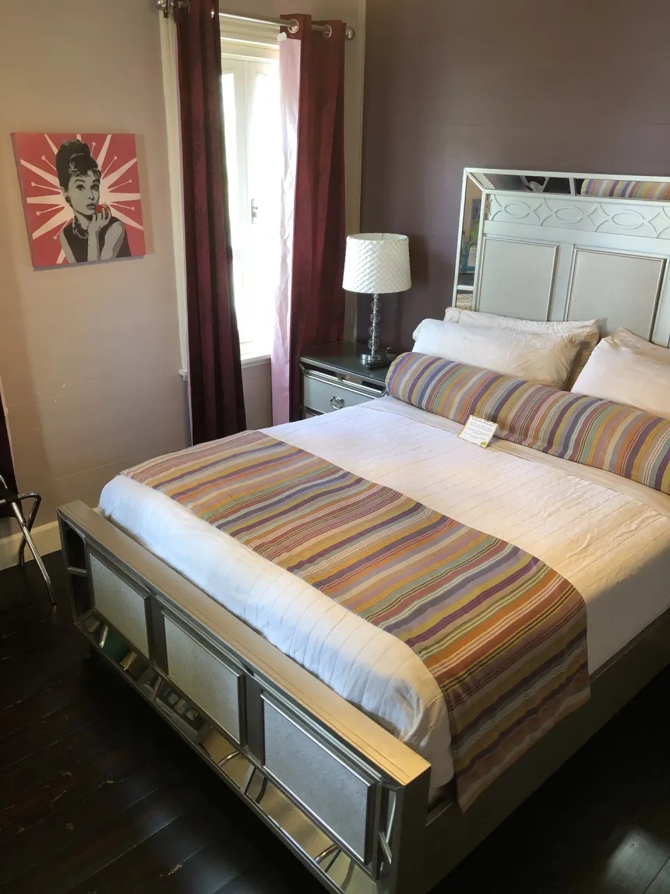 Guest room with mirrored king bed, striped runner, and window at The Fred.
