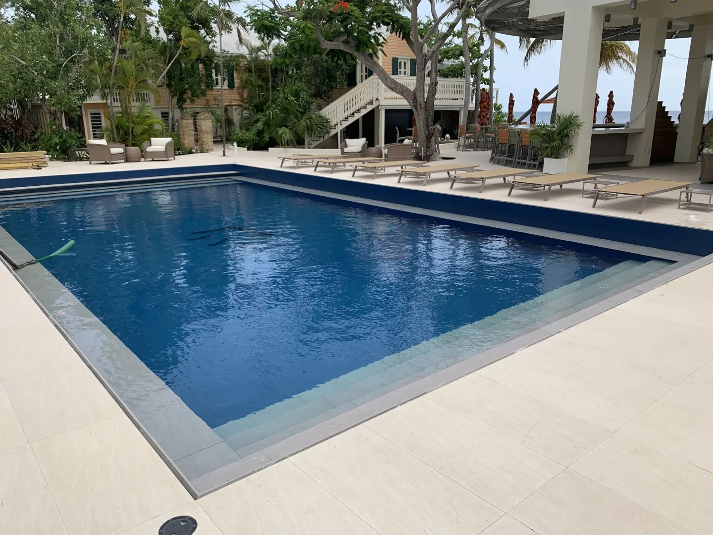 Rectangular pool with loungers, trees, and shaded bar area at The Fred.