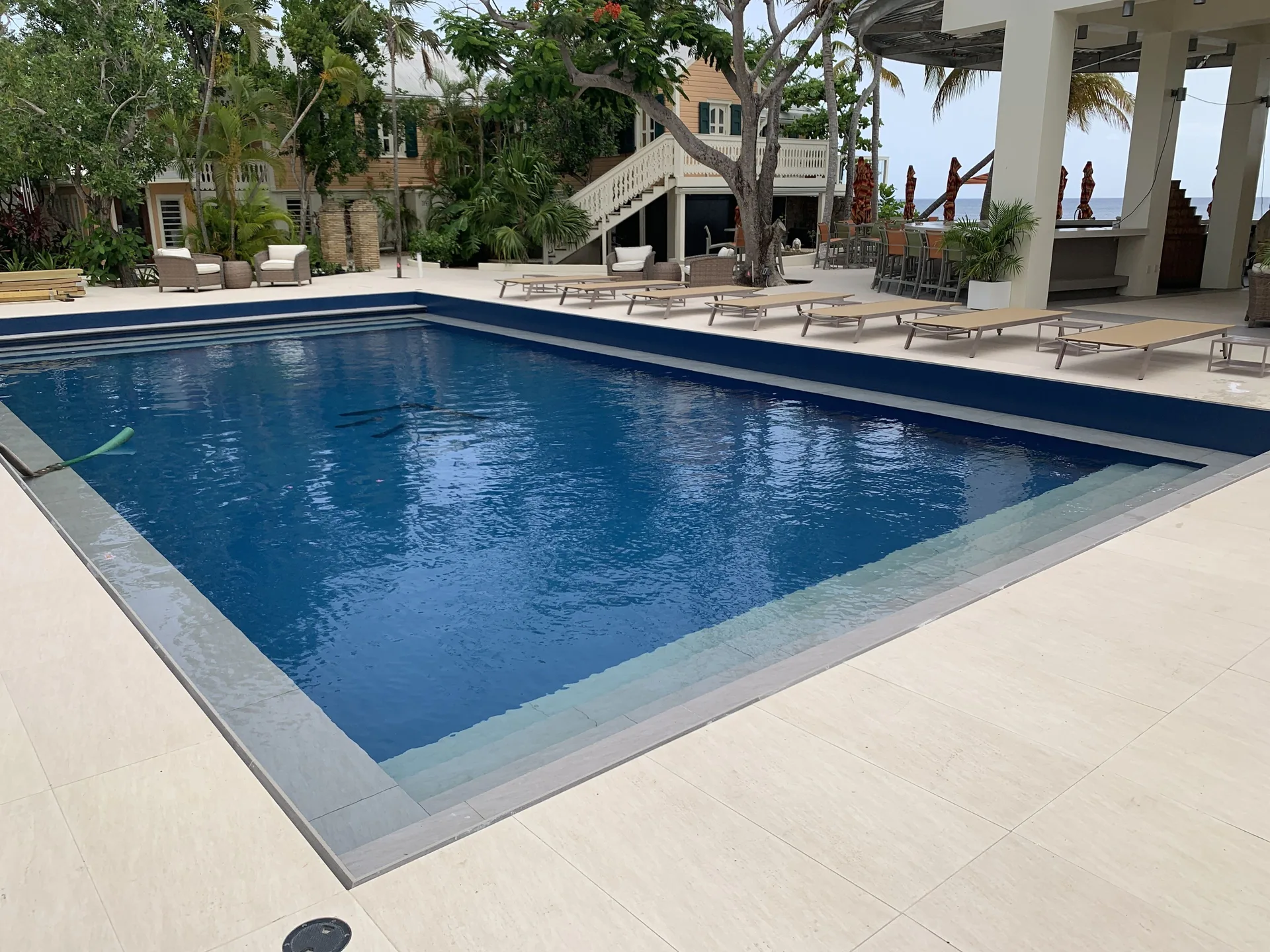 Rectangular pool with loungers, trees, and shaded bar area at The Fred.