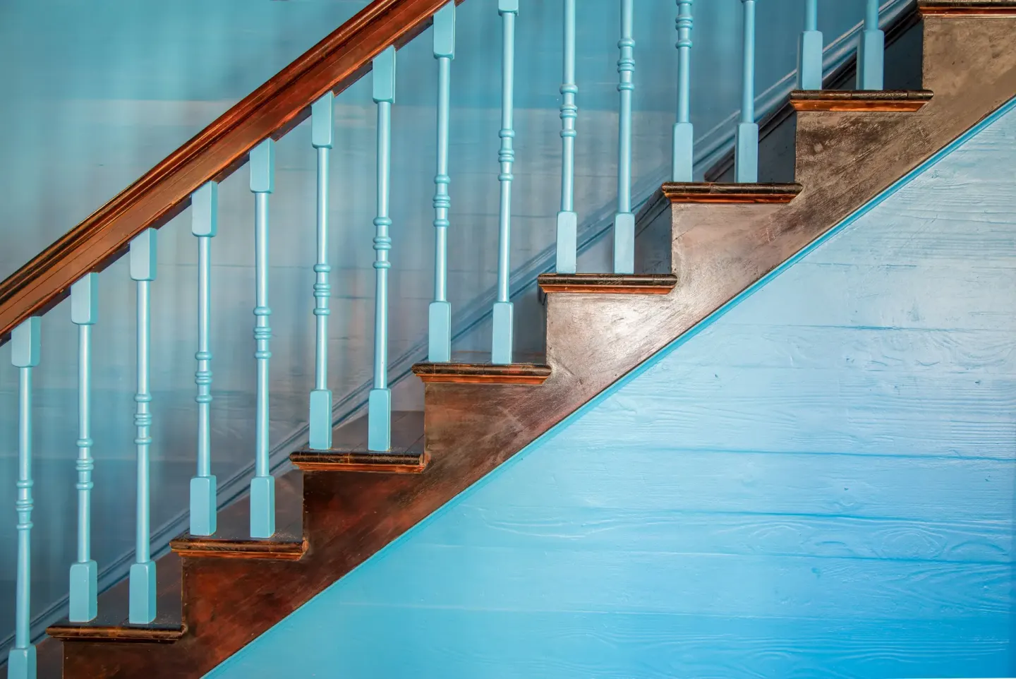 A turquoise staircase with dark wood treads and railings is shown at The Fred.
