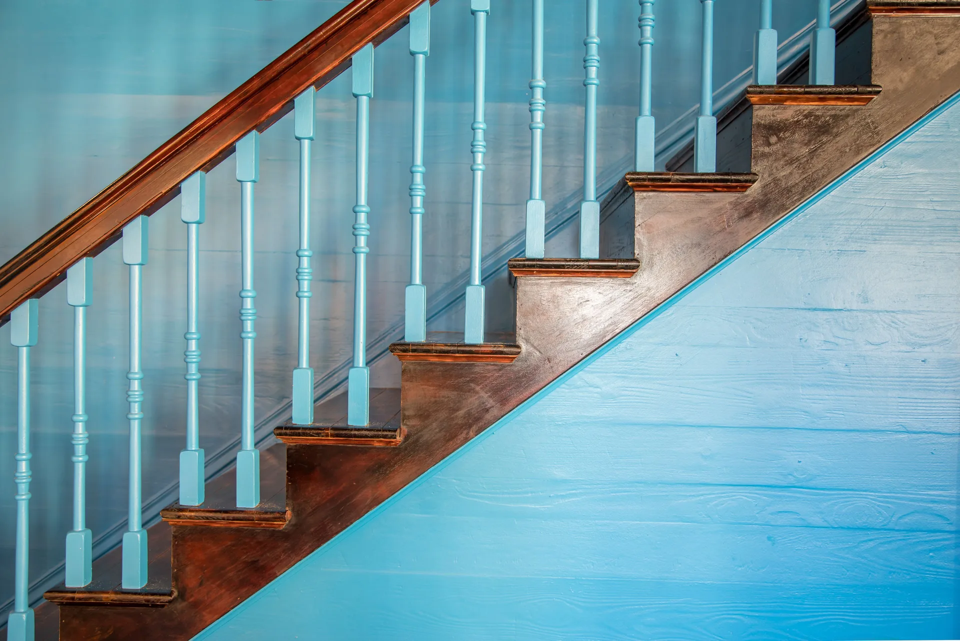 A turquoise staircase with dark wood treads and railings is shown at The Fred.