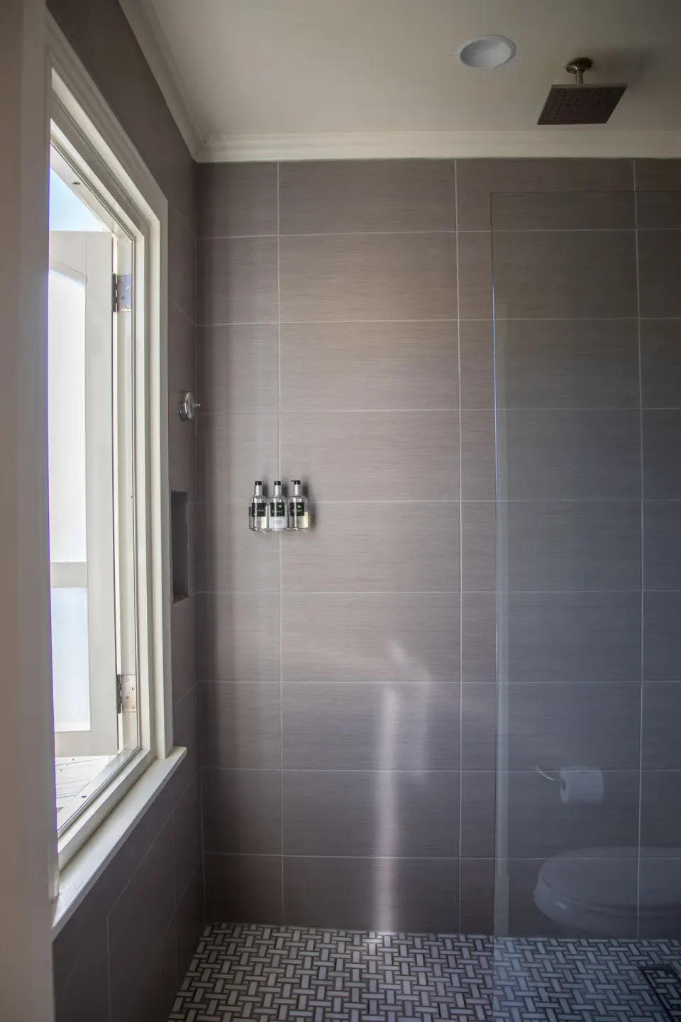 Basic Room Hill View Corner bathroom shower with gray tile and window at The Fred.