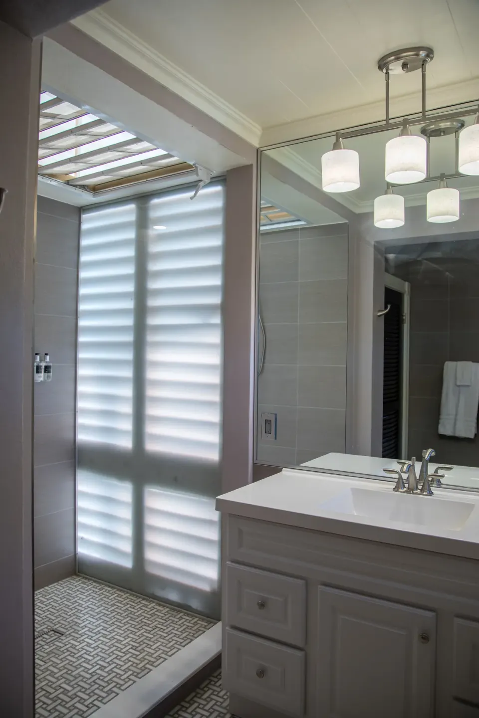 Basic Room Hill View Corner bathroom with vanity, mirror, and tiled shower at The Fred.