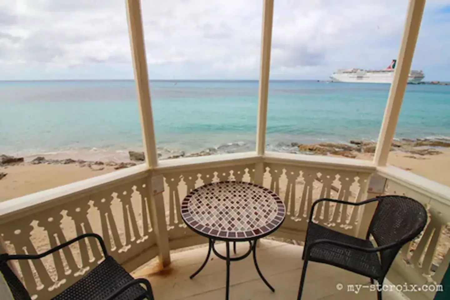 Covered Rachel balcony at The Fred with two chairs, a table, and sea view.