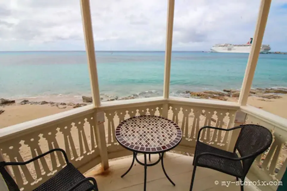 Covered Rachel balcony at The Fred with two chairs, a table, and sea view.