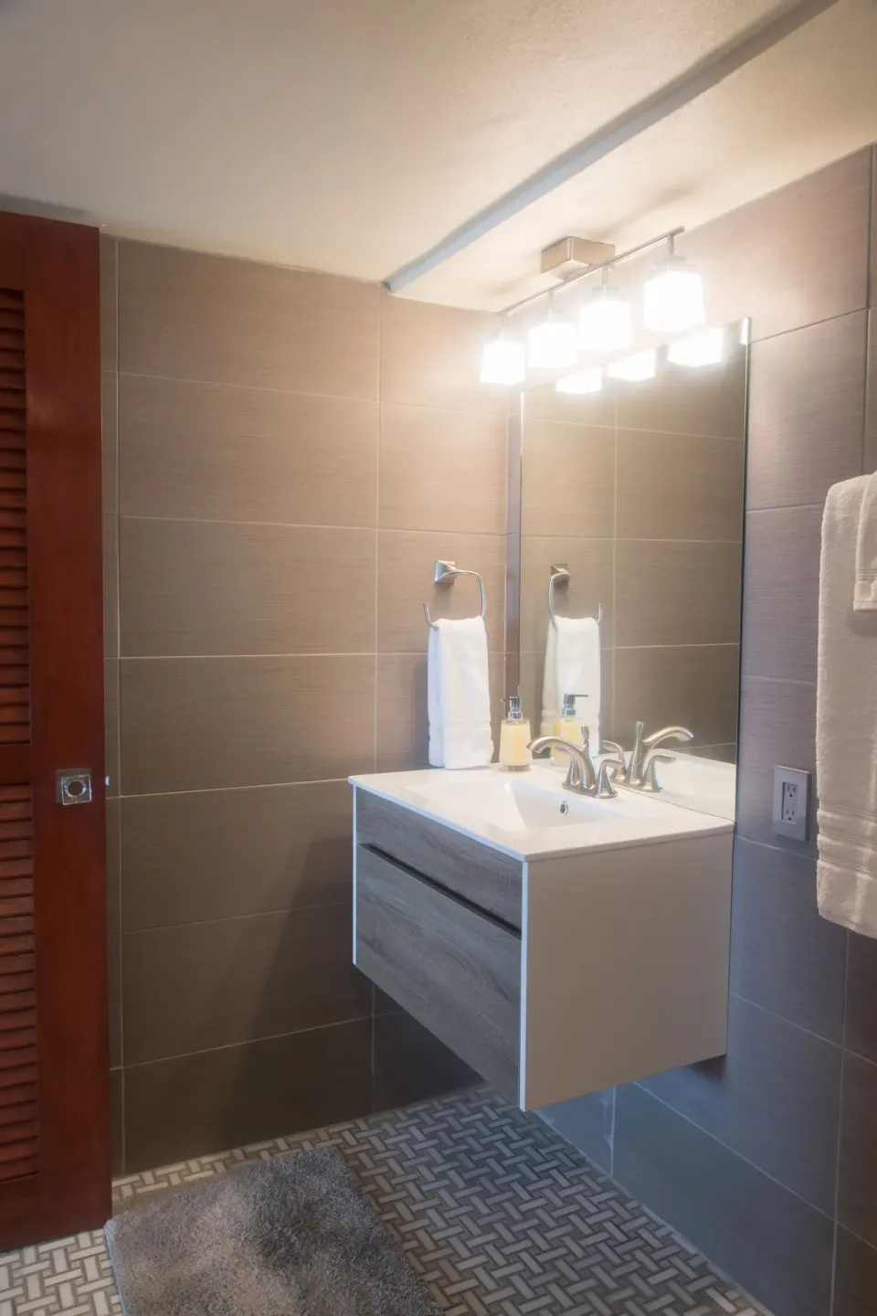 Honeymoon Suite bathroom vanity with illuminated mirror and patterned tile floor at The Fred.