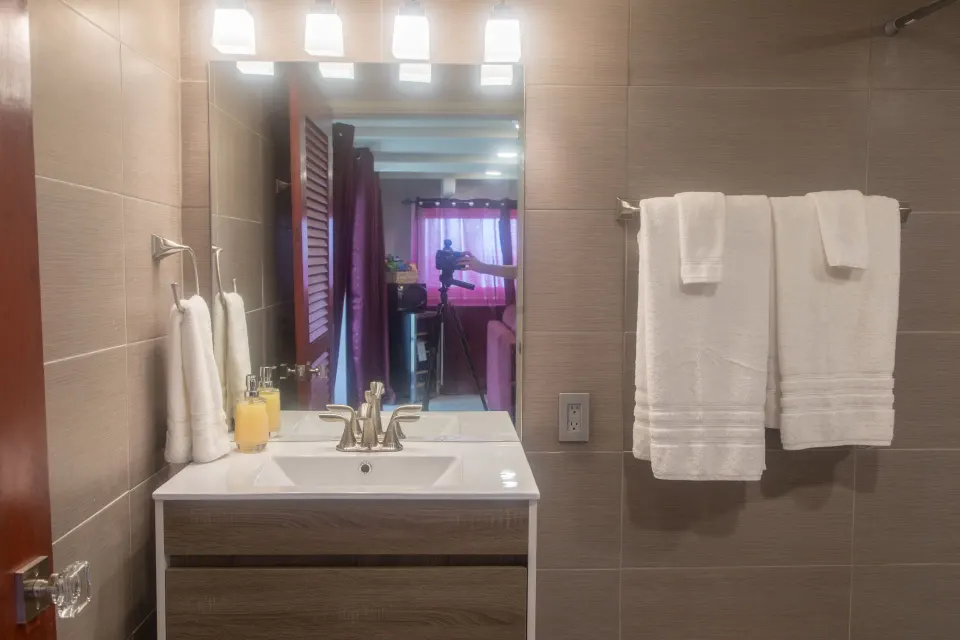 Honeymoon Suite bathroom vanity with mirror, towels, and tiled walls at The Fred.