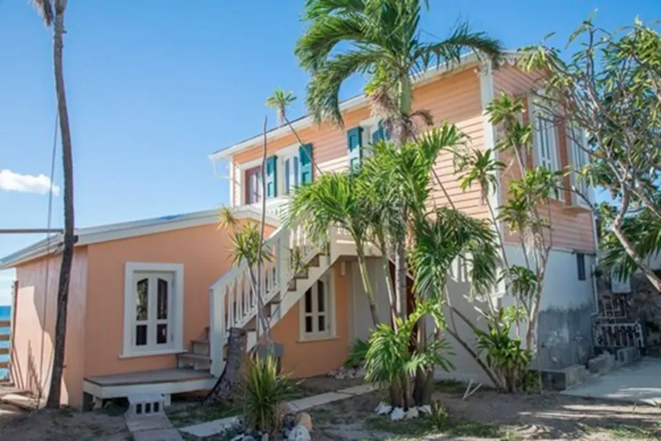 Exterior of The Fred suite building with peach walls, palms, and an outdoor staircase.