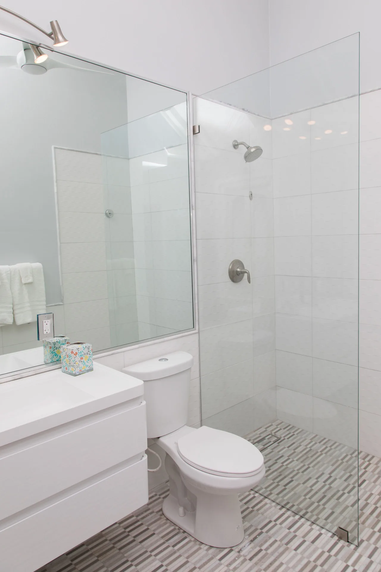 Premier Room Sea View bathroom at The Fred with a glass shower, large mirror, toilet, and white vanity.