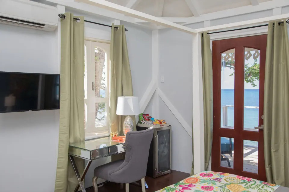 Premier Room Sea View at The Fred with a bed corner, desk, wall TV, and ocean-facing glass door.