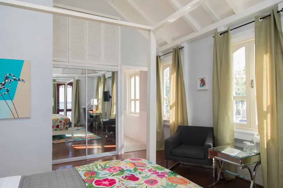 Premier Room Sea View at The Fred with floral bed, mirrored closet, armchair, and tall curtained windows.