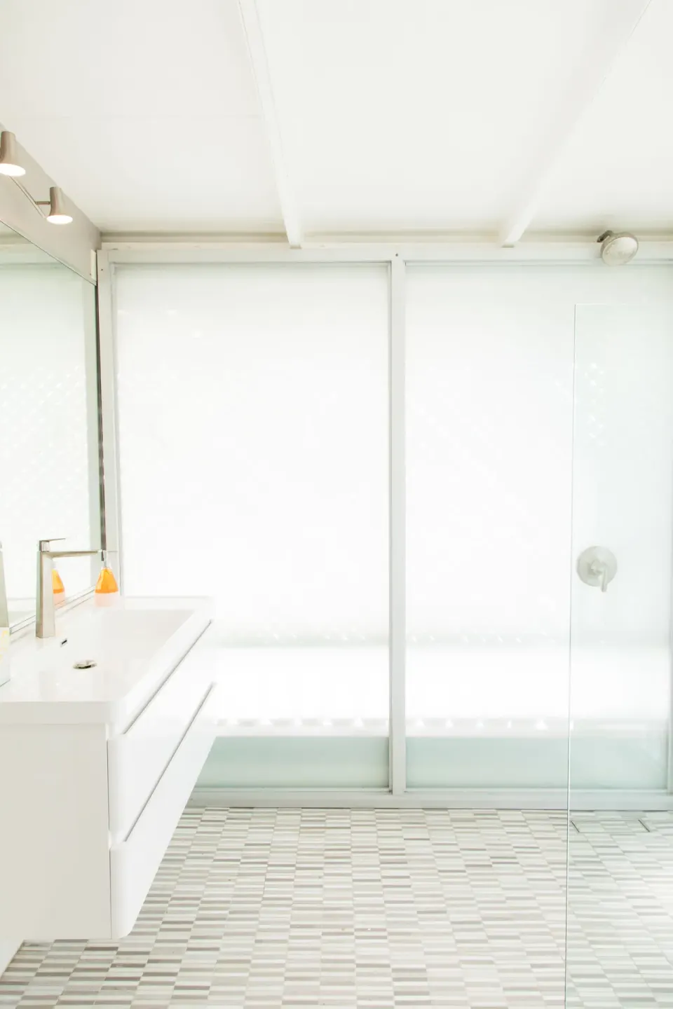 Bright white bathroom with tub and glass shower screen in a Premium room at The Fred.