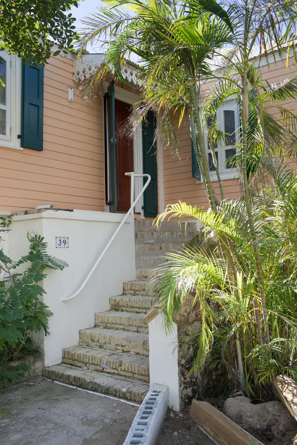Exterior entry to a Premium room at The Fred with steps, shutters, and tropical plants.
