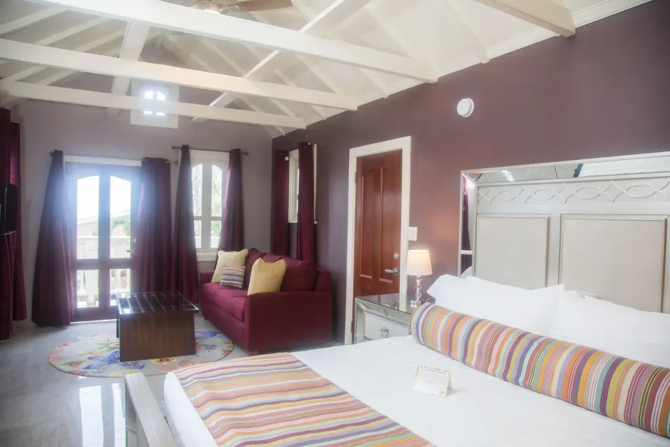 Premium studio suite king bed and sitting area beneath white beams at The Fred.
