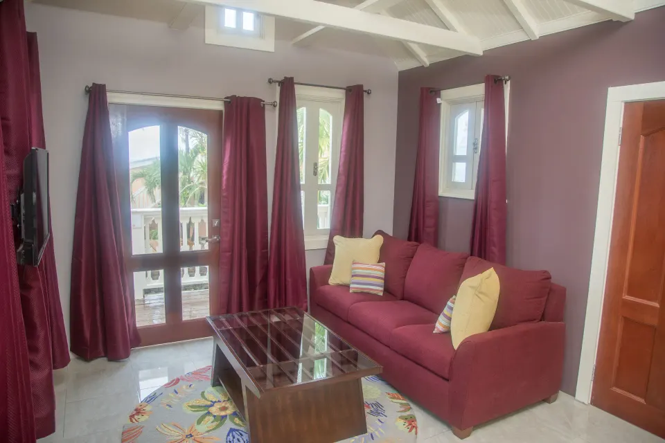 Premium studio suite sitting area with red sofa and balcony doors at The Fred.