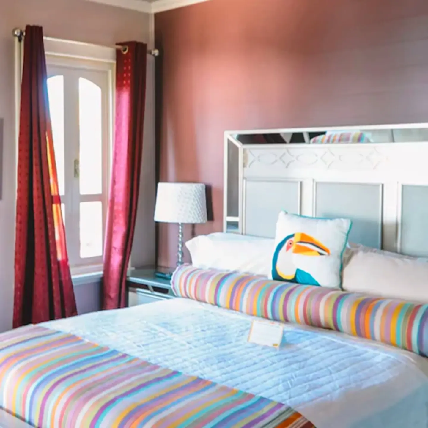 Close view of the Romantic Room bed with striped bolster and toucan pillow at The Fred.