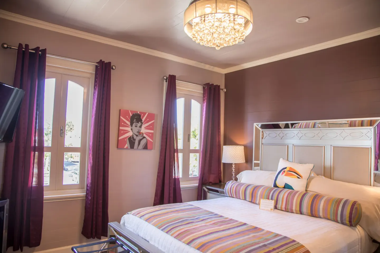 Milly romantic room bed with striped accents and tall windows at The Fred.