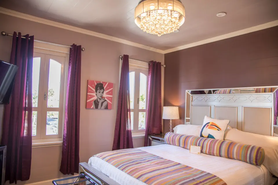 Milly romantic room bed with striped accents and tall windows at The Fred.