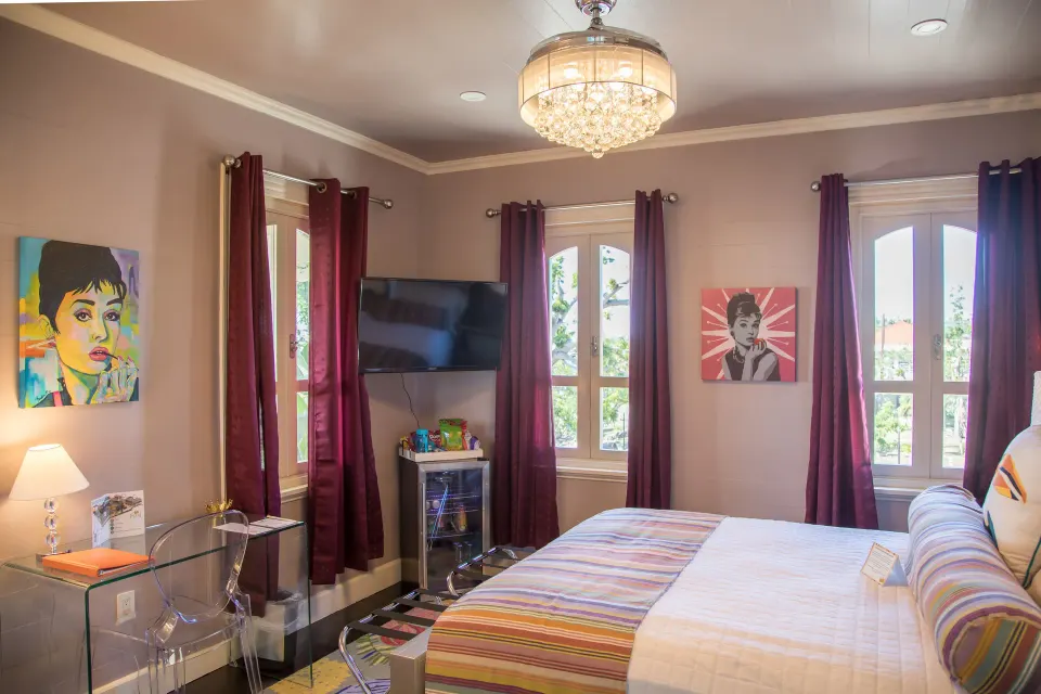 Romantic Room king bed, TV, desk, and tall curtained windows at The Fred.