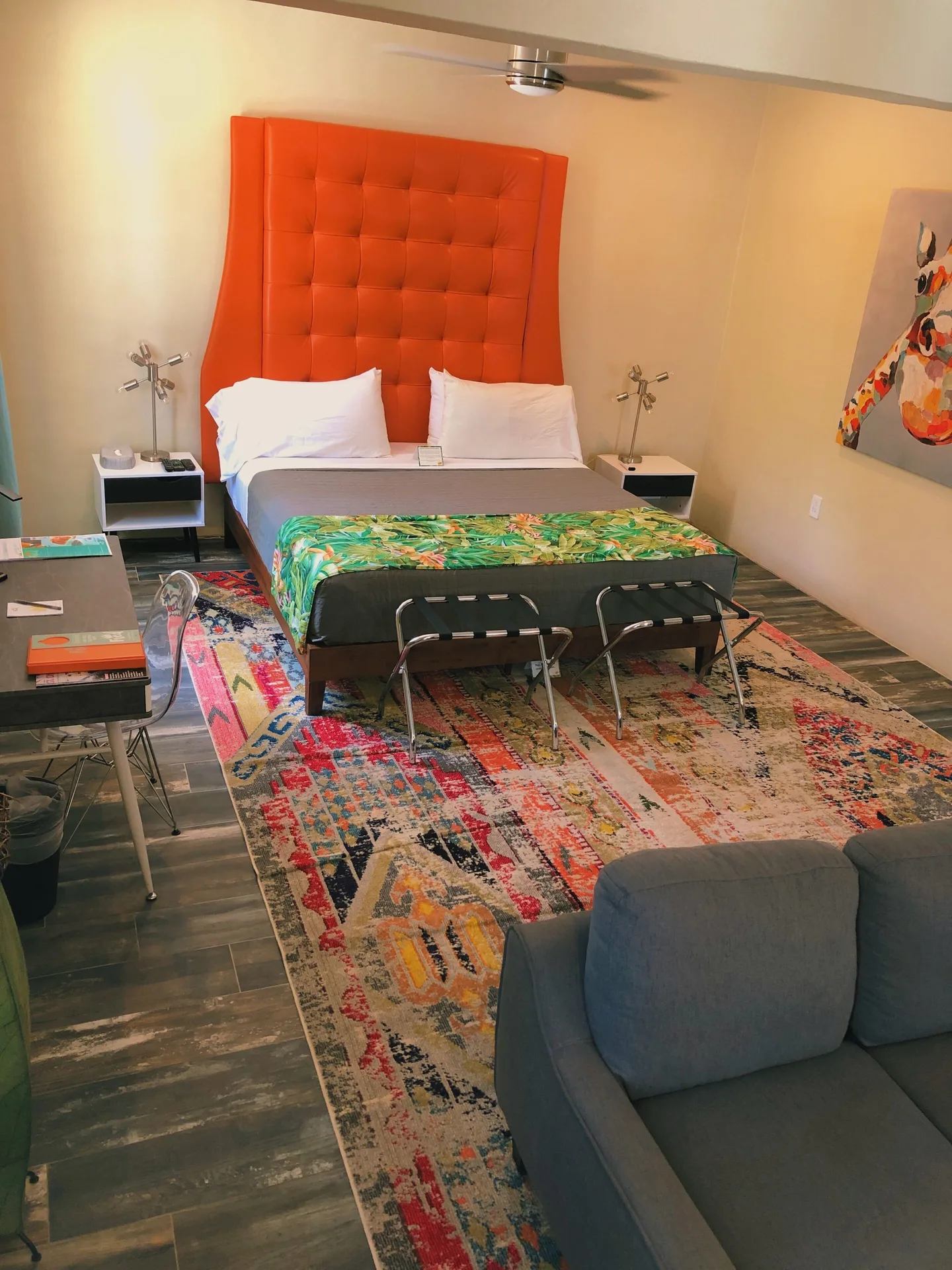 Signature Room with king bed, orange headboard, sofa, desk and colorful rug at The Fred.
