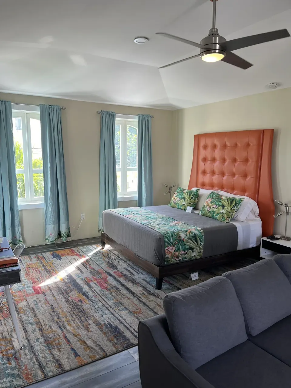 Signature Room at The Fred with king bed, orange tufted headboard, sofa, and tall windows.