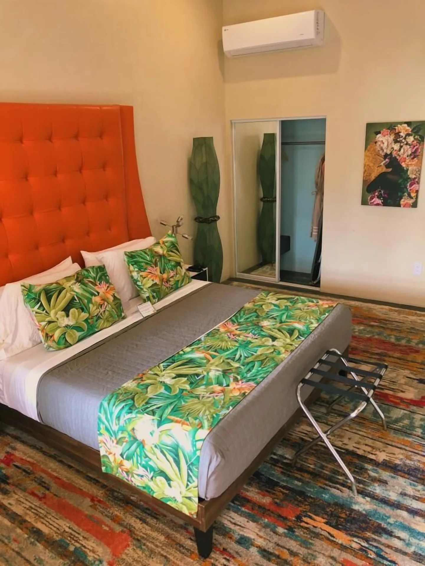 Signature Room at The Fred with king bed, orange headboard, closet mirrors and tropical linens.