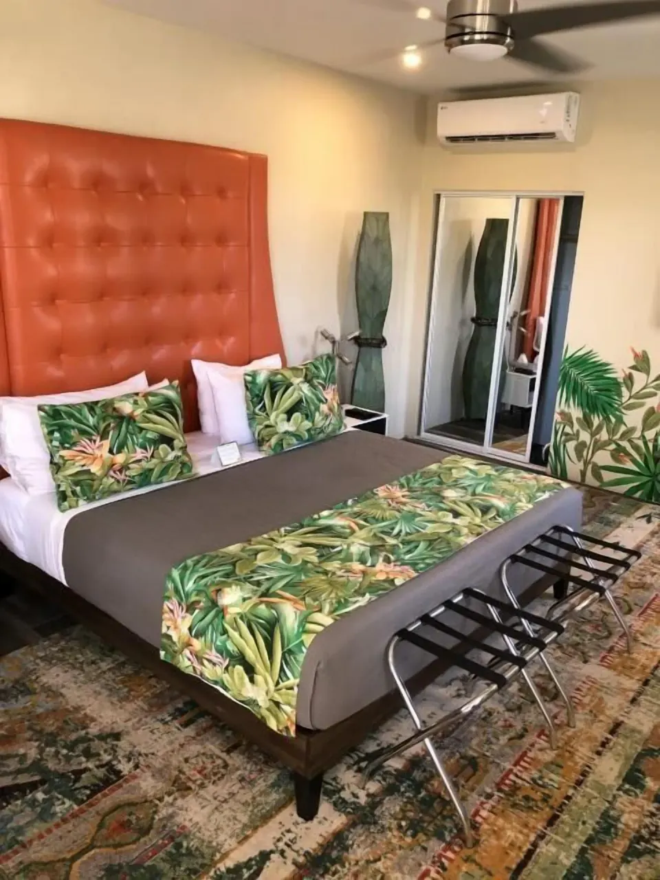 Signature Room Garden View king bed with tropical linens and orange headboard at The Fred.
